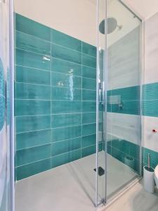 baño con ducha de cristal con azulejos azules en Villa Olea in Procida, en Procida