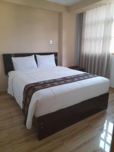 1 dormitorio con 1 cama grande con sábanas blancas y ventana en Mini apartamento valle sagrado yucay, en Cusco