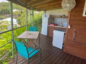 eine Küche mit einem Tisch und einem Tisch und Stühlen auf einer Terrasse in der Unterkunft KAZ AMOUR in Bouillante