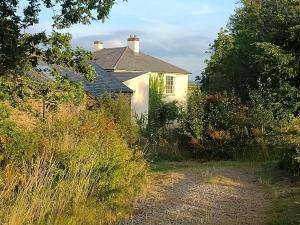 a white house with a pathway leading to it at Headson Farmhouse in Bratton Clovelly