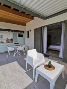 eine Terrasse mit einem Tisch, Stühlen und einem Bett in der Unterkunft Habitation I'SEO Adult Only in Sainte-Anne