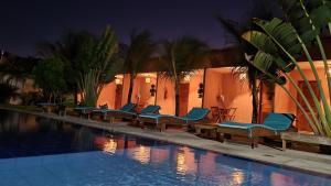 - une piscine avec des chaises longues bleues à côté d'un bâtiment dans l'établissement Pousada Bosque Cumbuco, à Cumbuco