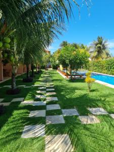 a garden with a stone path next to a swimming pool at Pousada Bosque Cumbuco in Cumbuco