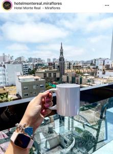 una persona che tiene una tazza di caffè sul balcone di Hotel Monte Real a Lima