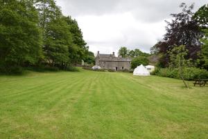 a field with a tent in front of a house at Sweetbriar Cottage Bed & Breakfast and Camping in Starbotton