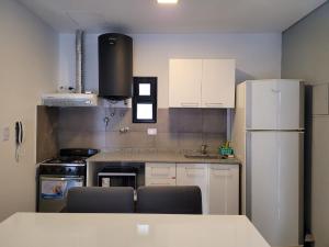 Una cocina con gabinetes blancos y un refrigerador blanco. en Departamento Céntrico muy cómodo, en San Juan