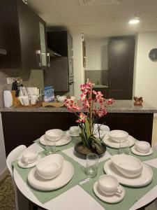 a table with white plates and glasses and flowers on it at Hawana apartment in Salalah