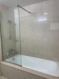 a bath tub with a glass shower door at Hawana apartment in Salalah