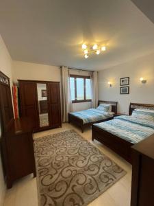 a bedroom with two beds and a rug at Hawana apartment in Salalah