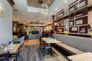 a restaurant with tables and chairs and a bar at Best Western Plus Toronto Airport Hotel in Mississauga