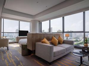 a living room with a couch and large windows at Pullman Suzhou Zhonghui in Suzhou