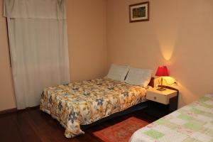 1 dormitorio con 1 cama y mesita de noche con lámpara en Casa Mendes en Gramado