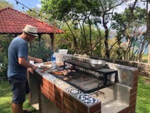 a man cooking food on a barbecue grill at Casa Única - Room with breakfast or Cabins with kitchen in La Laguna