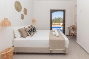 a white bedroom with a bed and a table at Luxury Villa Noesis with Pool and Seaview in Roussospítion