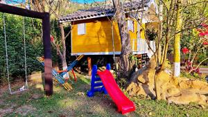 a childrens playground with a house and a slide at Chalés Poly in São Bento do Sapucaí