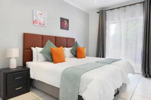1 dormitorio con 1 cama grande con almohadas de color naranja y verde en Prestigious Guest Villa, en Ciudad del Cabo