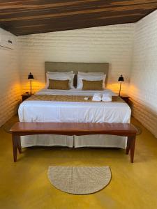 een slaapkamer met een groot bed en een houten tafel bij Casa Pé na Areia Maracajau in Maxaranguape