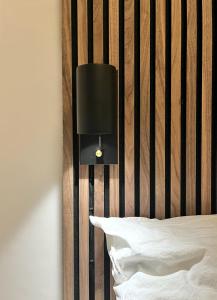 une lampe noire sur un mur à côté d'un lit dans l'établissement LE-Host, à Leipzig