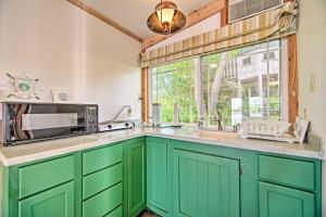 cocina con armarios verdes, fregadero y ventana en Peaceful Horicon Studio with Rock River Access!, en Juneau