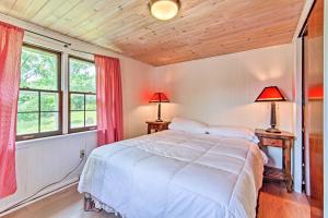 a bedroom with a white bed and two windows at Charming Horicon Cottage and Dock on Rock River in Juneau