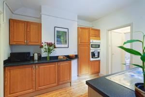 a kitchen with wooden cabinets and a black counter top at Cosy 1-Bed Escape with Free Parking - At Hem in Winchester +2 photos