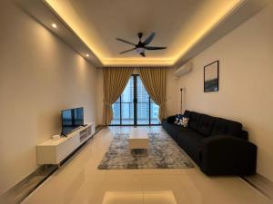 a living room with a black couch and a ceiling fan at R&F Princess Cove by StayHere - 3BR in Johor Bahru