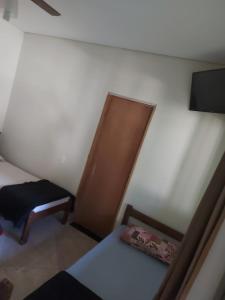 a small bedroom with a bed and a chair at Pousada Tropical in Aparecida