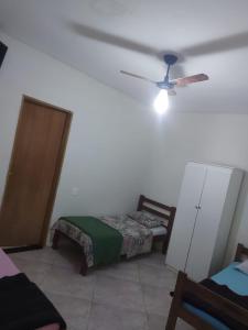 a room with a bed and a ceiling fan at Pousada Tropical in Aparecida