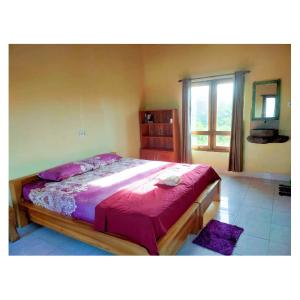 ein Schlafzimmer mit einem Bett mit violetter Bettwäsche und einem Fenster in der Unterkunft Medewi Surf And Stay in Airsatang