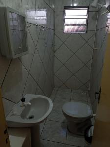 a white bathroom with a sink and a toilet at Apartamento com churrasqueira, ótima localização. in Cachoeira do Sul