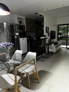a kitchen and living room with a glass table and chairs at Apt perto da praia com vaga e serv de arrumadeira in Rio de Janeiro