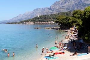 a group of people on a beach in the water at Apartments by the sea Podgora, Makarska - 6671 in Podgora