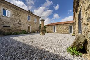 une cour d'un ancien bâtiment en pierre avec un pilier en pierre dans l'établissement Nomad's Country - 4BED Casa de Macieira, à Santa Maria da Feira