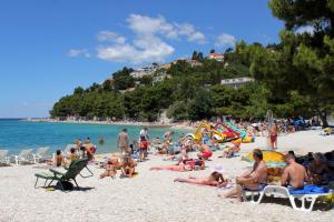 a group of people sitting on a beach at Apartments with parking space Baska Voda, Makarska - 2609 in Baška Voda