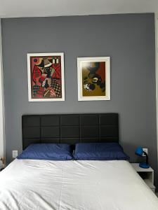 a bedroom with a bed with two pictures on the wall at Apt perto da praia com vaga e serv de arrumadeira in Rio de Janeiro