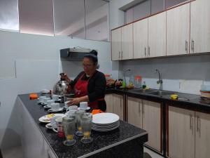 una mujer parada en una cocina preparando comida en Hotel Real Bolivar, en Chimbote