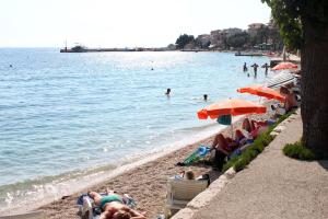 a beach with people sitting in lawn chairs and umbrellas at Apartments with a parking space Gradac, Makarska - 13196 in Gradac