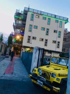 a yellow jeep parked in front of a building at Gems Palace Hotel Sost in Gircha