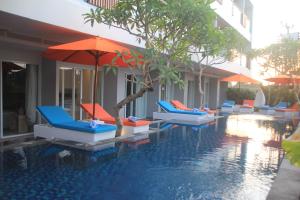 a swimming pool with lounge chairs and umbrellas at Destiny Boutique Hotel in Seminyak