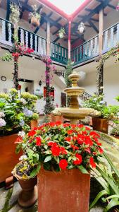 Hotel San Gabriel في El Cocuy: مجموعة من الزهور في الأواني في غرفة مع نافورة