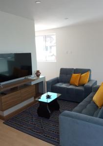a living room with a couch and a tv and a table at Buena Vista Apartment in Cusco