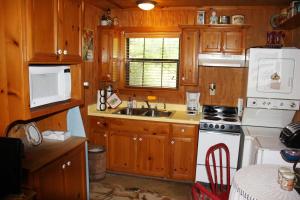 a kitchen with wooden cabinets and a white stove top oven at Double U Barr Ranch - Cowboy Cabin in Bandera