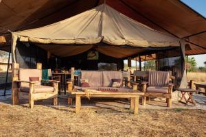 a large tent with chairs and a table and a bench at Gnu Mara River Camp in Serengeti