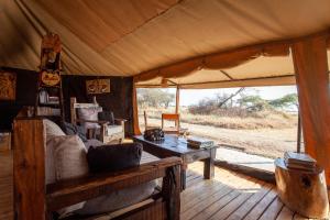 a room with a couch and a table in a tent at Mawe Tented Camp in Serengeti