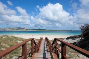 a wooden boardwalk to a beach with a view at Rocca Ruja Vip in Stintino