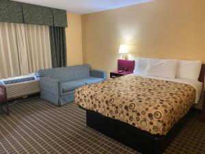 Habitación de hotel con cama y silla en America's Stay Inn Stewartville, en Stewartville