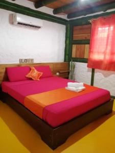 1 dormitorio con 1 cama grande con sábanas de color rosa y naranja en Aparthotel Oleaje, en Mompiche