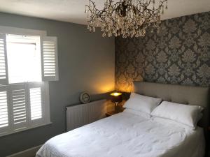 a bedroom with a white bed and a chandelier at Homely Victorian Terraced Town House with Parking. in Taunton