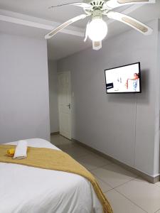 una camera da letto con ventilatore a soffitto e TV a parete di EYEZULU Guesthouse a Pinetown