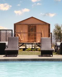 ein Resort mit einem Pool, 2 Stühlen und einem Haus in der Unterkunft Indomito Resort & Hotel Boutique in Valle de Guadalupe